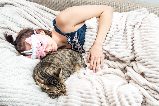 kat sover sammen med kvinde i seng